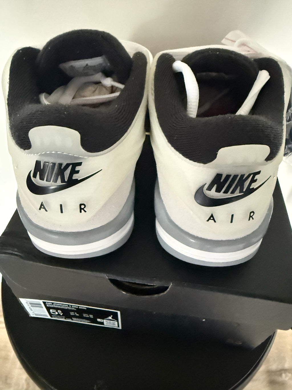 D’s Laces Jordan 4 RM sneakers in light bone and white, showing the rear heel view with black Nike Air branding.